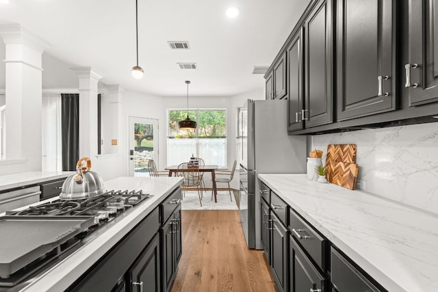 13300 Country Lake Dr, Austin, TX 78732 - kitchen featuring backsplash, appliances with stainless steel finishes, visible vents, and light wood-style floors