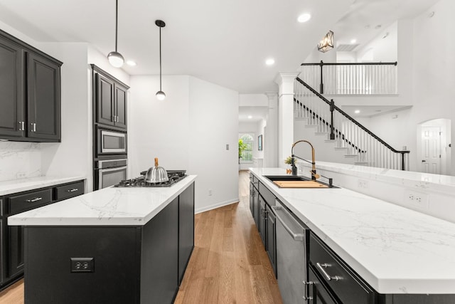 13300 Country Lake Dr, Austin, TX 78732 - kitchen featuring a spacious island, light wood-type flooring, dark cabinetry, a sink, and stainless steel appliances
