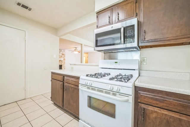 kitchen featuring visible vents, light countertops, stainless steel microwave, white range with gas cooktop, and light tile patterned flooring