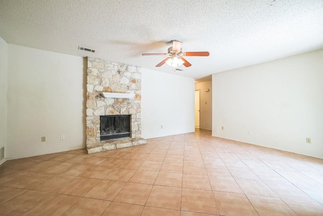 unfurnished living room featuring a textured ceiling, ceiling fan, visible vents, and a stone fireplace