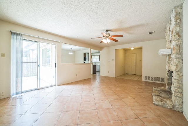 unfurnished living room with a ceiling fan, light tile patterned flooring, a textured ceiling, and visible vents