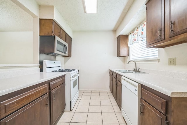 kitchen featuring white appliances, a textured ceiling, a sink, and light countertops