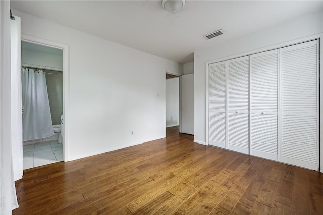 8221 Renton Dr, Austin, TX 78757 - unfurnished bedroom with wood finished floors, a closet, connected bathroom, and baseboards