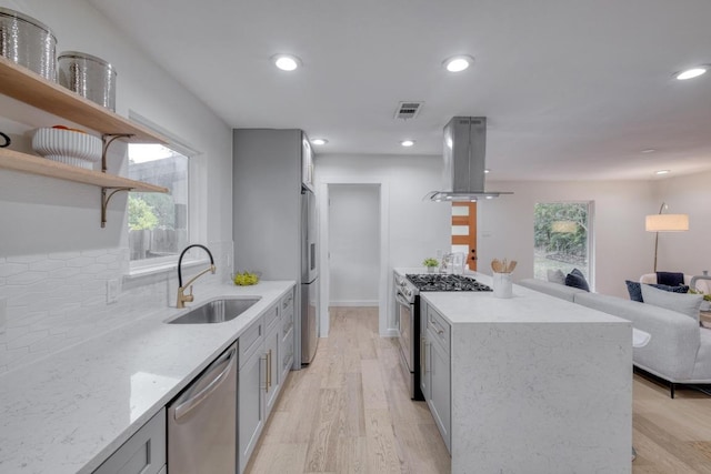 kitchen with open shelves, a sink, stainless steel appliances, open floor plan, and island range hood