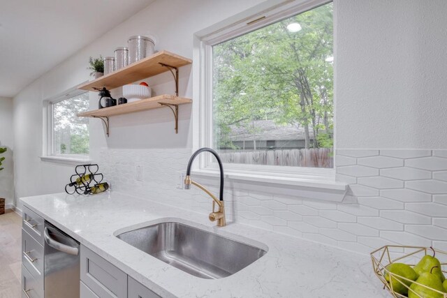 5307 Downs Dr, Austin, TX 78721 - kitchen with a sink, stainless steel dishwasher, light stone counters, and tasteful backsplash
