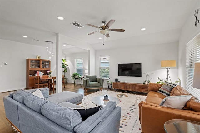 living area featuring plenty of natural light, light wood finished floors, ceiling fan, and visible vents