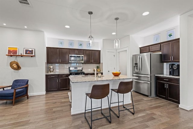 kitchen featuring visible vents, dark brown cabinets, a sink, light wood finished floors, and stainless steel appliances