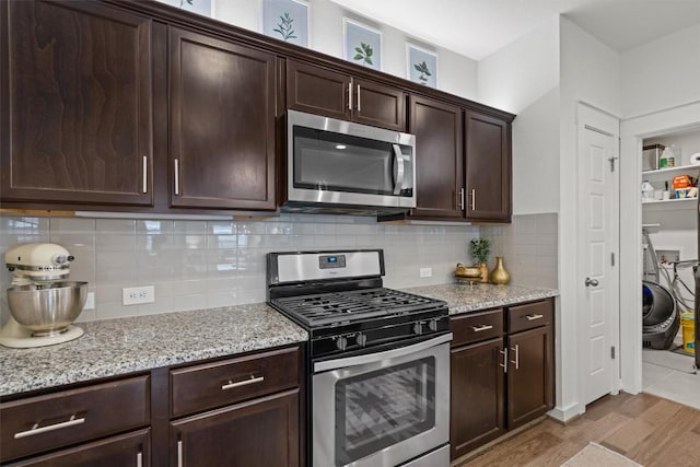 kitchen with dark brown cabinetry, appliances with stainless steel finishes, light stone counters, light wood finished floors, and decorative backsplash