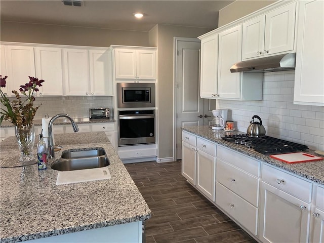 kitchen featuring appliances with stainless steel finishes, a sink, a toaster, under cabinet range hood, and white cabinetry