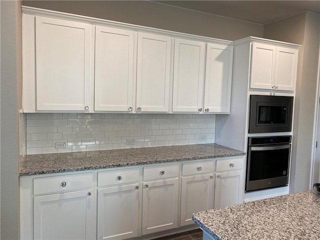 kitchen featuring white cabinetry, backsplash, light stone countertops, and stainless steel appliances