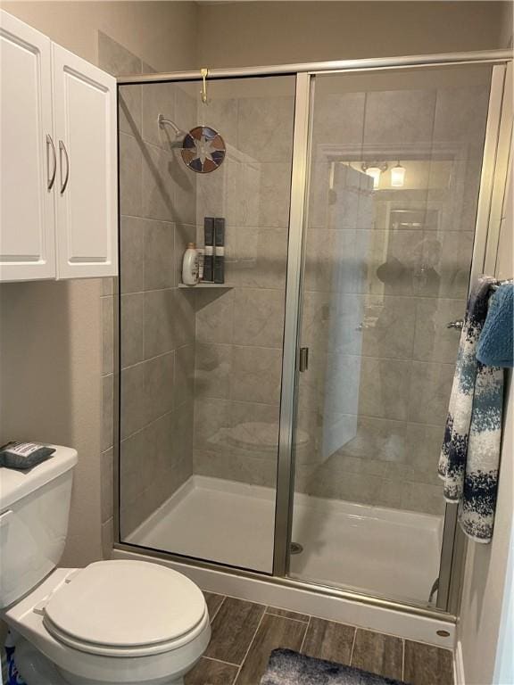 full bathroom with toilet, wood finished floors, and a stall shower