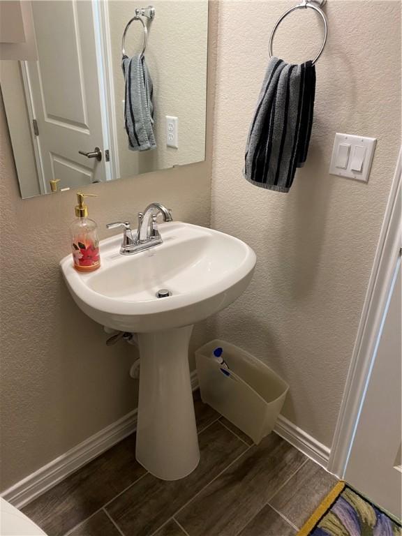 bathroom with baseboards, a textured wall, and wood finished floors