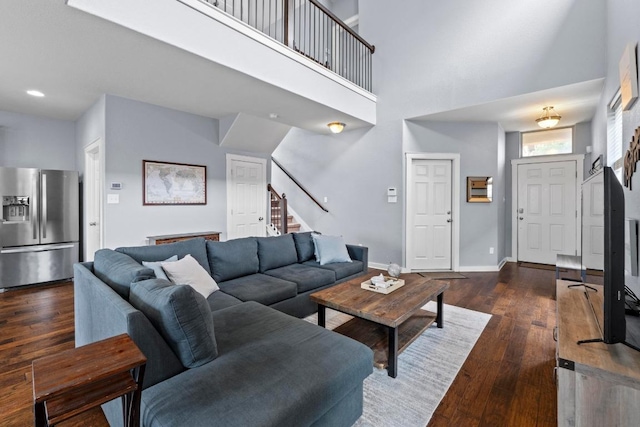living room with recessed lighting, baseboards, dark wood-type flooring, a towering ceiling, and stairway