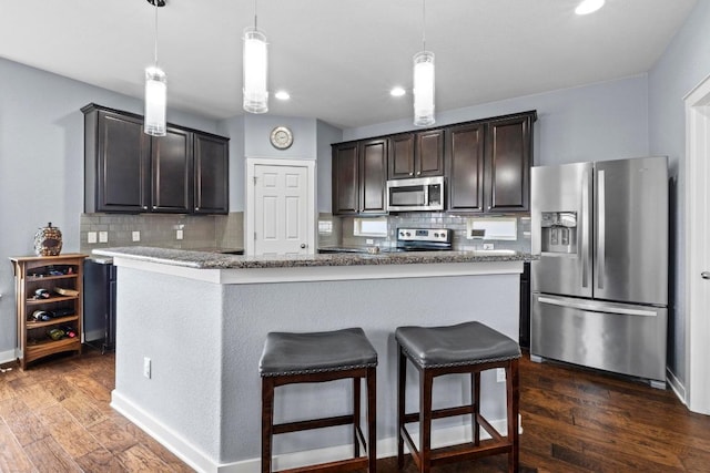 kitchen with dark wood-style flooring, stainless steel appliances, dark brown cabinets, and tasteful backsplash