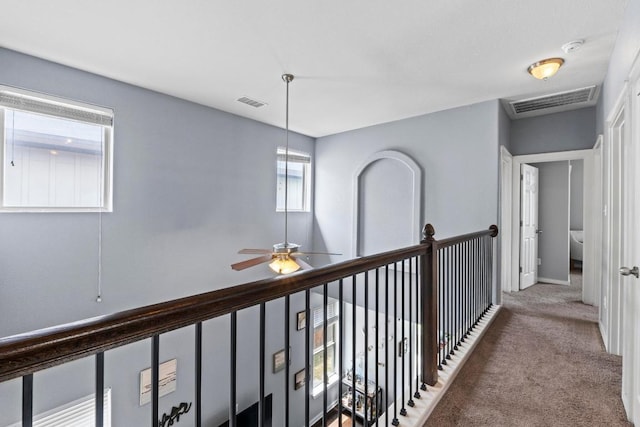 hallway featuring baseboards, carpet flooring, and visible vents