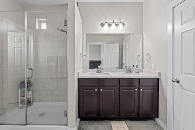 bathroom featuring double vanity, a sink, baseboards, and a stall shower