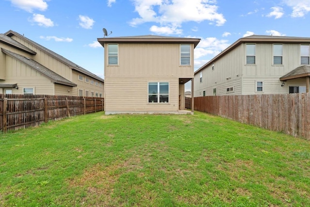 rear view of house featuring a fenced backyard and a lawn