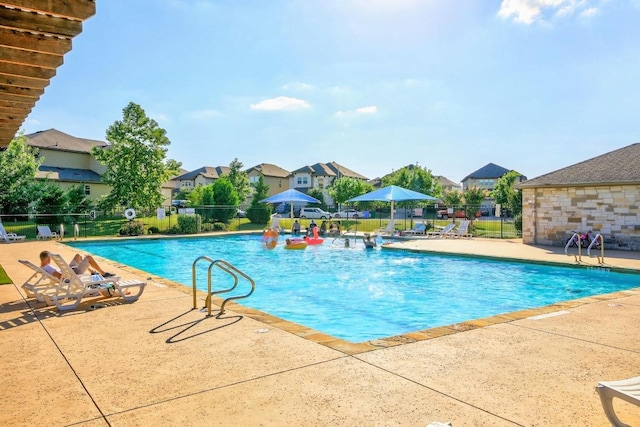 community pool featuring fence, a patio area, and a residential view