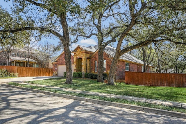 240 Fort Mabry Loop, Georgetown, TX 78628 - view of front of home with a front yard, a garage, brick siding, fence, and concrete driveway