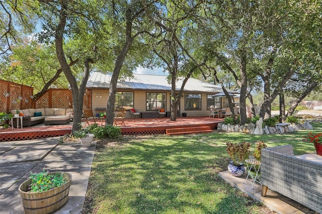back of house with a standing seam roof, a deck, an outdoor living space, a lawn, and metal roof
