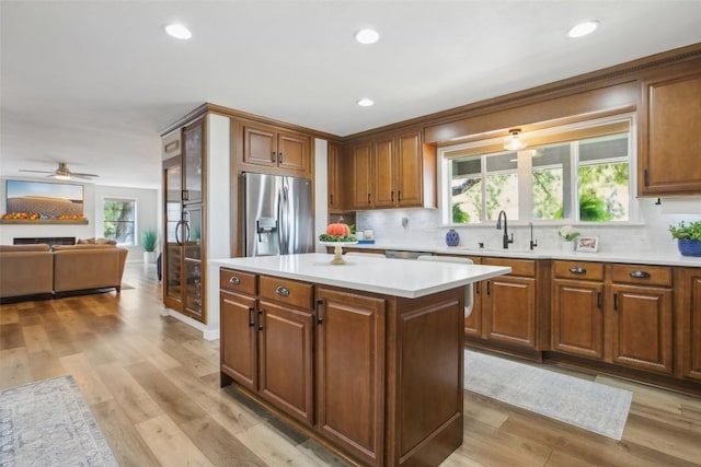kitchen featuring light countertops, stainless steel refrigerator with ice dispenser, decorative backsplash, and a sink