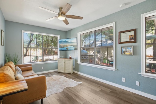 sitting room with baseboards, ceiling fan, and wood finished floors