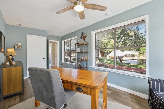 office space with a healthy amount of sunlight, baseboards, a ceiling fan, and visible vents