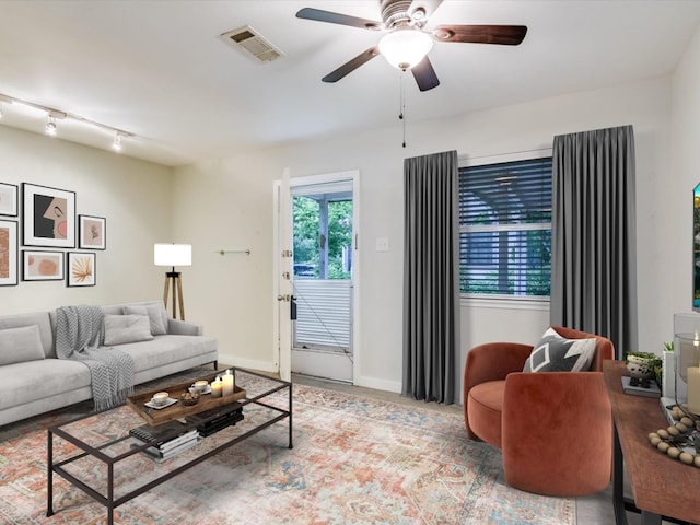 living room with ceiling fan, visible vents, track lighting, and baseboards
