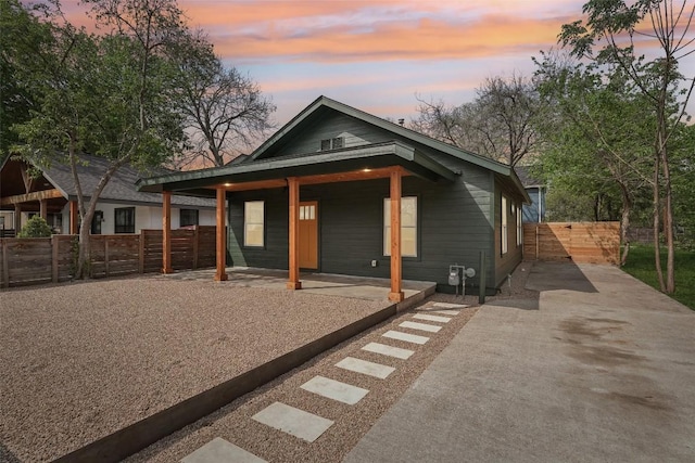view of front facade featuring covered porch, fence, and driveway