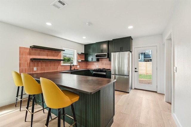 kitchen featuring dark countertops, appliances with stainless steel finishes, open shelves, a sink, and visible vents