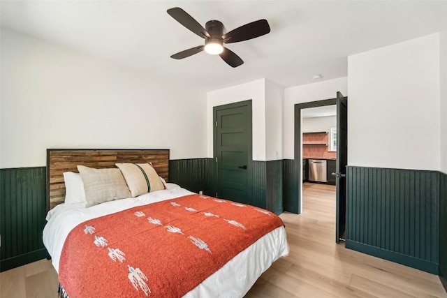 bedroom featuring a ceiling fan, wainscoting, and light wood-style flooring