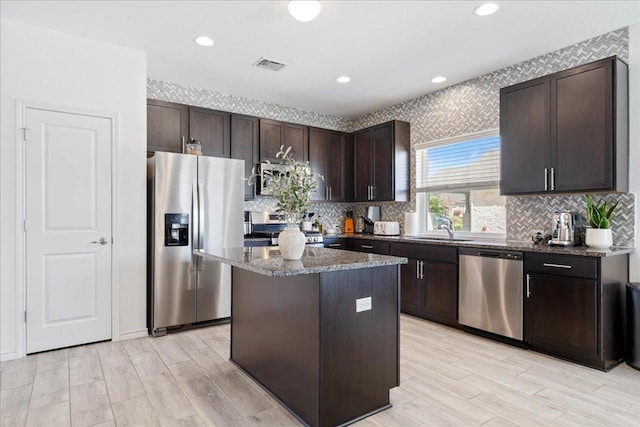 9015 Looksee Ln, Austin, TX 78744 - kitchen featuring light wood-style floors, a sink, dark stone countertops, and stainless steel appliances