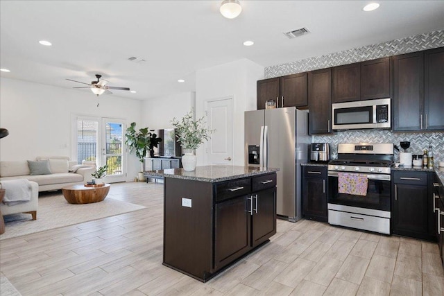 9015 Looksee Ln, Austin, TX 78744 - kitchen featuring decorative backsplash, a ceiling fan, visible vents, open floor plan, and stainless steel appliances
