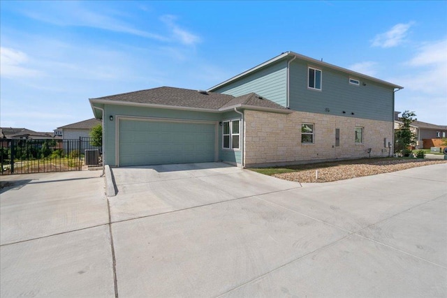 9015 Looksee Ln, Austin, TX 78744 - view of home's exterior with driveway, an attached garage, stone siding, and central AC unit