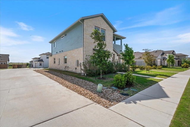 9015 Looksee Ln, Austin, TX 78744 - view of home's exterior with stone siding, a residential view, concrete driveway, and a lawn