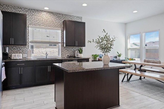 9015 Looksee Ln, Austin, TX 78744 - kitchen featuring a sink, a center island, backsplash, light wood-style floors, and dark stone counters