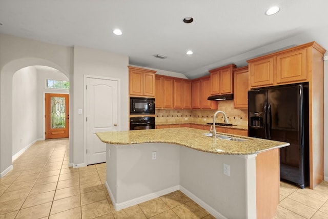 kitchen with visible vents, decorative backsplash, under cabinet range hood, arched walkways, and black appliances