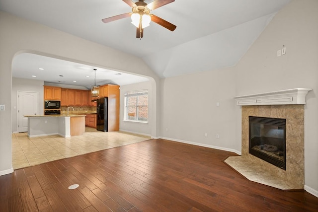 unfurnished living room with baseboards, a sink, and light wood-style flooring