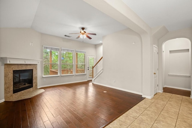 unfurnished living room featuring visible vents, a fireplace, baseboards, stairway, and a ceiling fan