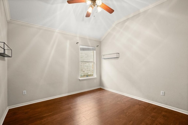 empty room featuring a ceiling fan, vaulted ceiling, wood finished floors, baseboards, and ornamental molding
