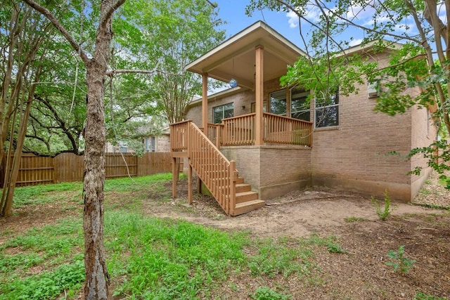 back of house featuring brick siding, fence, stairway, and a deck