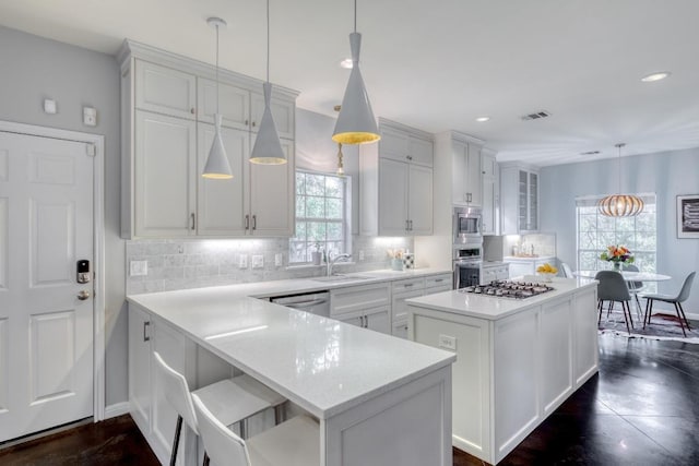 kitchen featuring a kitchen island, white cabinets, tasteful backsplash, a sink, and appliances with stainless steel finishes