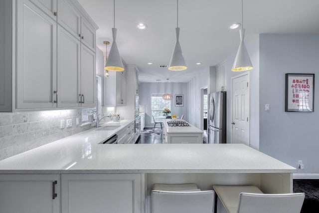 kitchen featuring a sink, a center island, stainless steel appliances, white cabinetry, and decorative backsplash