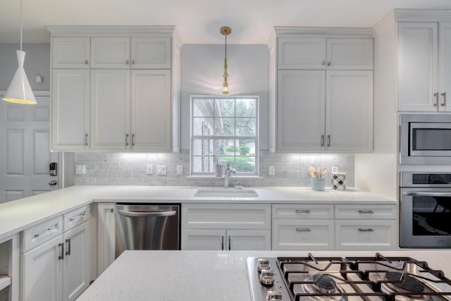 kitchen with white cabinets, a sink, backsplash, decorative light fixtures, and stainless steel appliances