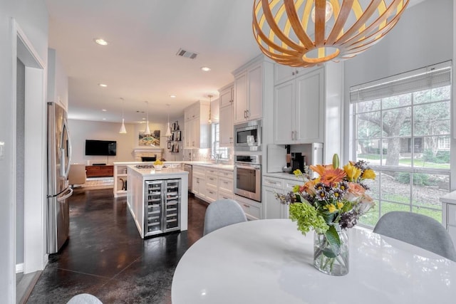 4511 Heights Dr, Austin, TX 78746 - kitchen featuring appliances with stainless steel finishes, a center island, beverage cooler, light countertops, and recessed lighting
