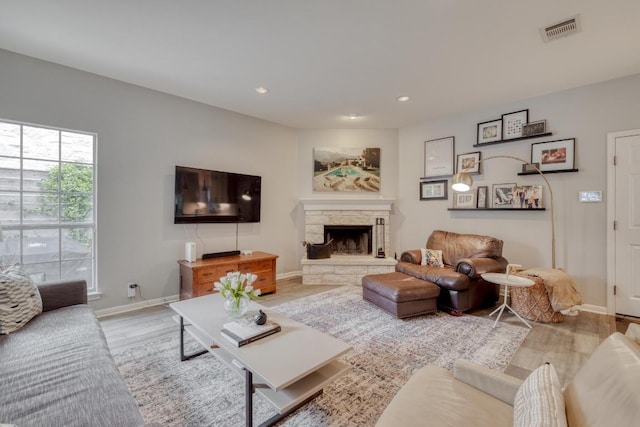 living area featuring baseboards, visible vents, light wood-style floors, and a fireplace