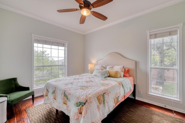 bedroom featuring crown molding, baseboards, wood finished floors, and multiple windows