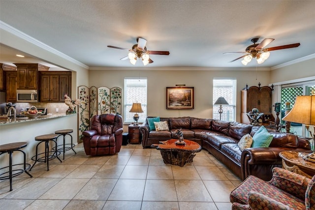 living area with crown molding, light tile patterned floors, and a ceiling fan