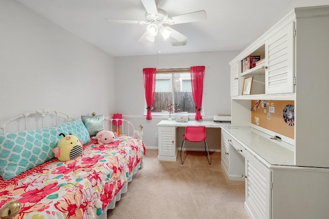 bedroom featuring ceiling fan, visible vents, light colored carpet, built in study area, and baseboards