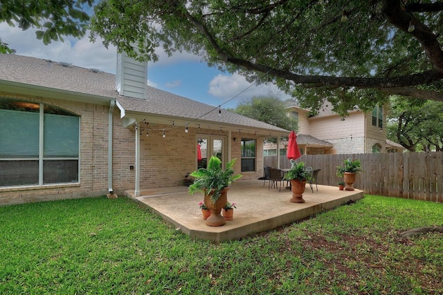 back of house with a lawn, fence, a chimney, and a patio